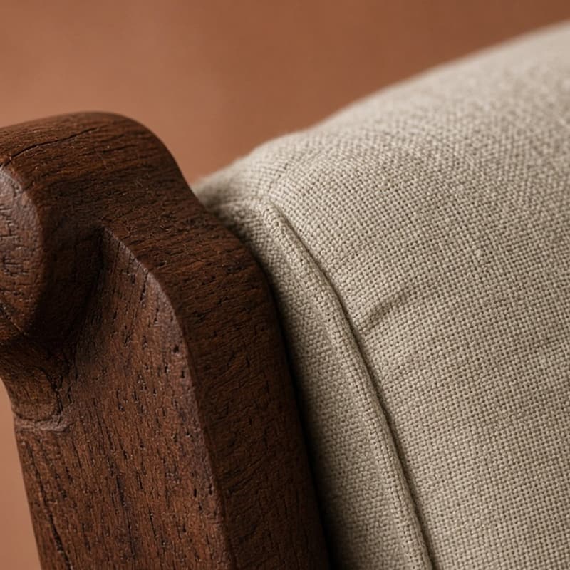 Close detail of a carved oak arm meeting woven upholstery